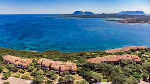 A coastal resort with terracotta-roofed buildings, lush greenery, and clear blue waters. - Welcomely - Porto Rotondo sul Mare (Olbia)