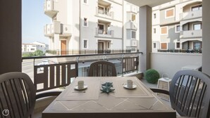 A balcony with a table set for two, chairs, and a small potted plant. - Welcomely - Xenia Boutique House - Apt 7 (Olbia)