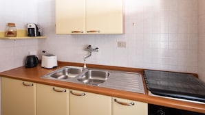 Una cocina con un lavamanos doble, un tostador, una cafetera y un microondas.