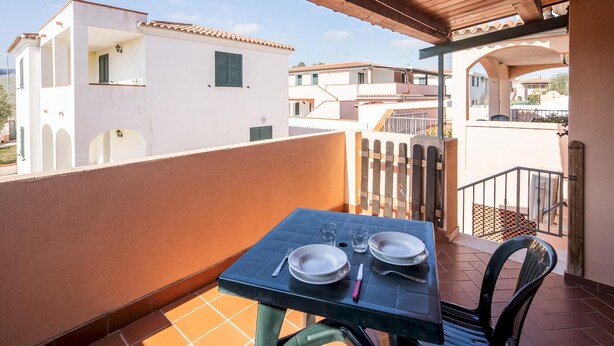 Un balcón con una mesa para dos, una silla y vistas a edificios cercanos.
