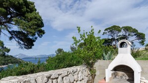 A stone wall and a stone oven with a view of the sea and mountains in the background. - Apartments Skurla - Studio Apartman (Mljet)