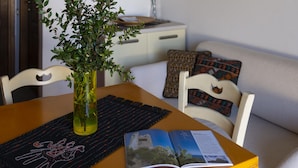 A dining table with a plant in a glass vase, a placemat, and an open magazine. - Welcomely - Sa Murta-il Mirto (Tortoli)