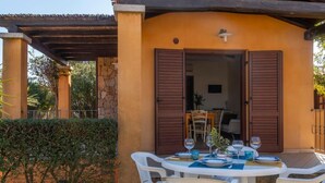An outdoor dining area with a table set for four, surrounded by white chairs, under a pergola. - Welcomely - Sa Murta-il Mirto (Tortoli)