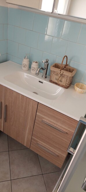 A bathroom with a white sink, wooden cabinets, and light blue tiles.