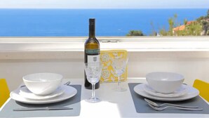 A table set with white bowls, a wine bottle, and glasses on a balcony with a view of the ocean. - Apartment Miriam - Studio Apartment With Sea View (Dubrovnik)