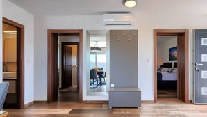 Een modern interieur met een houten vloer, een centrale airconditioning en een eetgedeelte zichtbaar door een open deur.