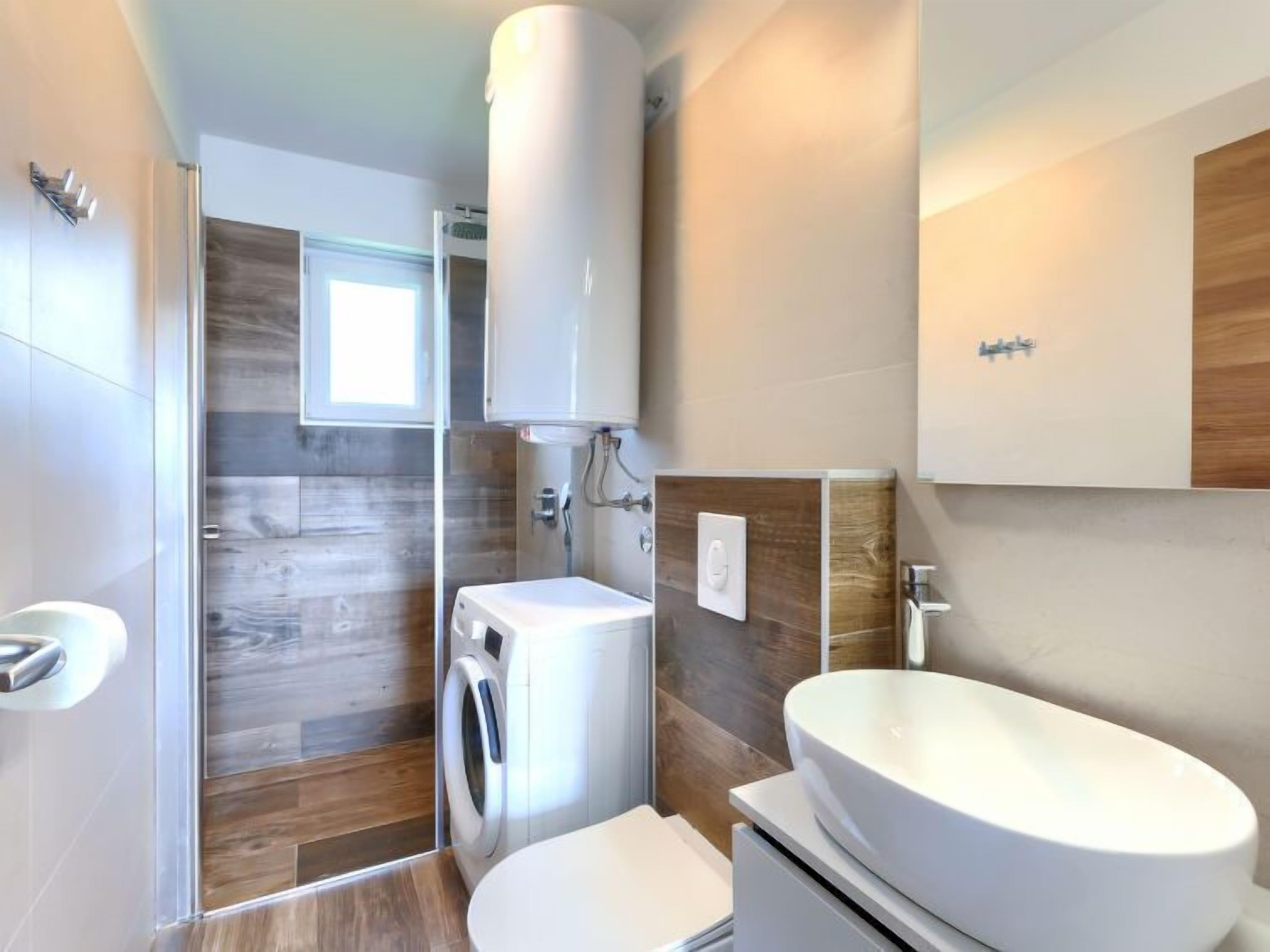 A modern bathroom with a built-in washing machine, a toilet, and a sink.