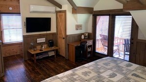 Un dormitorio acogedor con una cama grande, vigas de madera en el techo, un escritorio con silla, televisor y una zona de café.