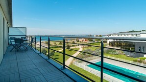 A balcony with a view of a swimming pool and a distant body of water. - Les Thermes 532 - Vue mer avec piscine partagée (Concarneau)