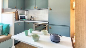 Eine kleine Küche mit türkisblauen Schränken, einer weißen Arbeitsplatte und einem eingebauten Backofen.