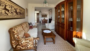 A living room with a patterned sofa, a wooden coffee table, and a cabinet with glass doors. - Welcomely - Casa Vania (Bolotana)