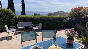 A patio with a table set for two, a bottle of wine, and a plate of food. - Casa Damiano by Interhome (Imperia)