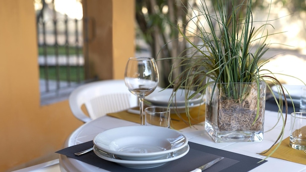 Mesa lista para comer, con platos, cubiertos y un vaso de agua.