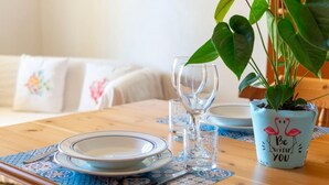 Uma mesa de jantar posta com pratos, copos e um vaso de planta.