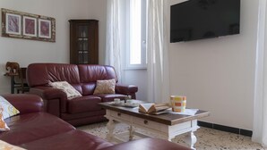Un salon avec un canapé en cuir, une table basse en bois et un téléviseur fixé au mur.