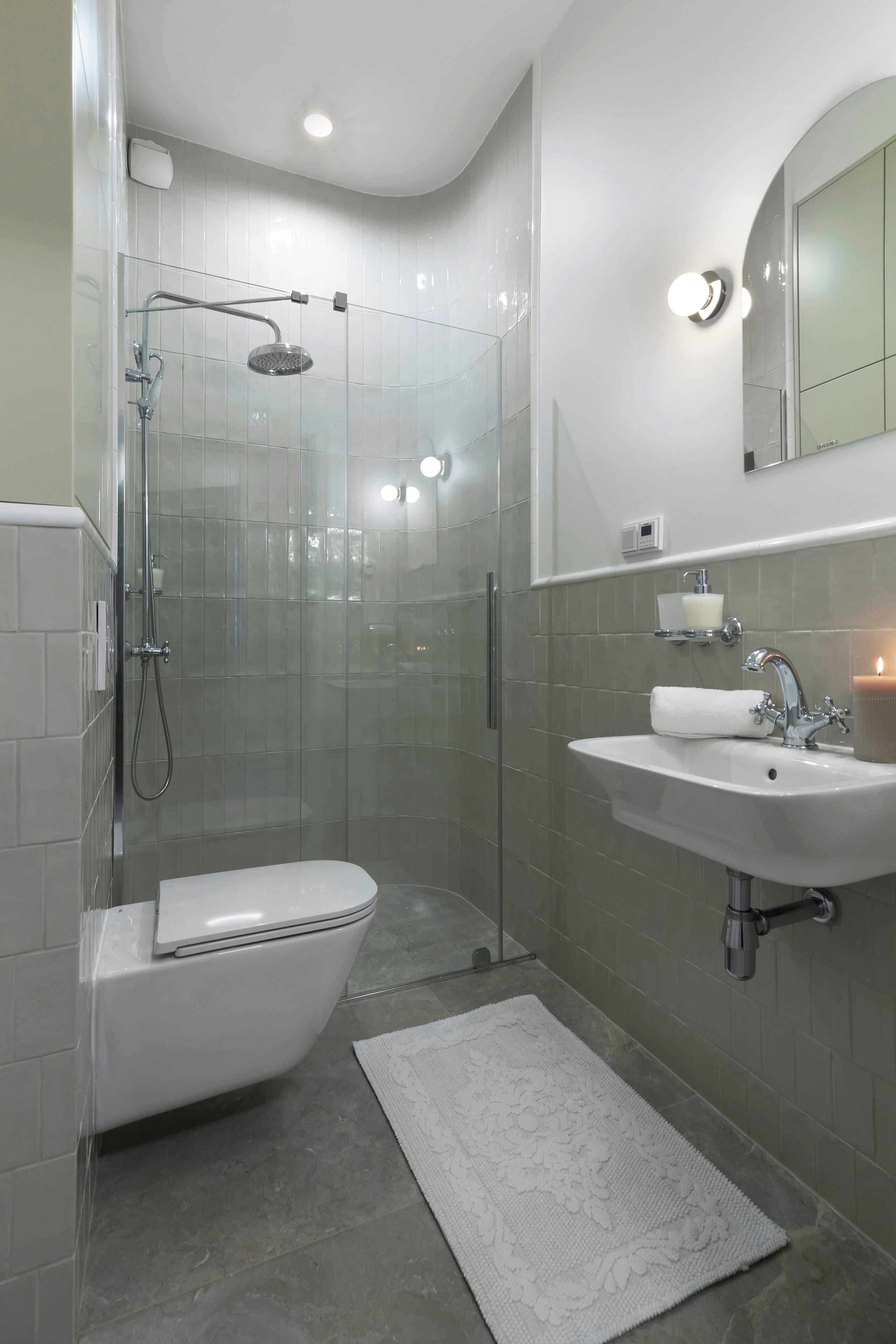A modern bathroom with a glass-enclosed shower, a white toilet, and a sink with a mirror above it.