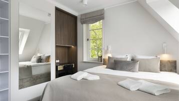 Ein Schlafzimmer mit einem großen Bett, einem Kleiderschrank, einem Schreibtisch und einem Fenster mit Blick auf Bäume.