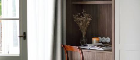 A wooden desk with a vase of dried flowers, a book, and a candle.