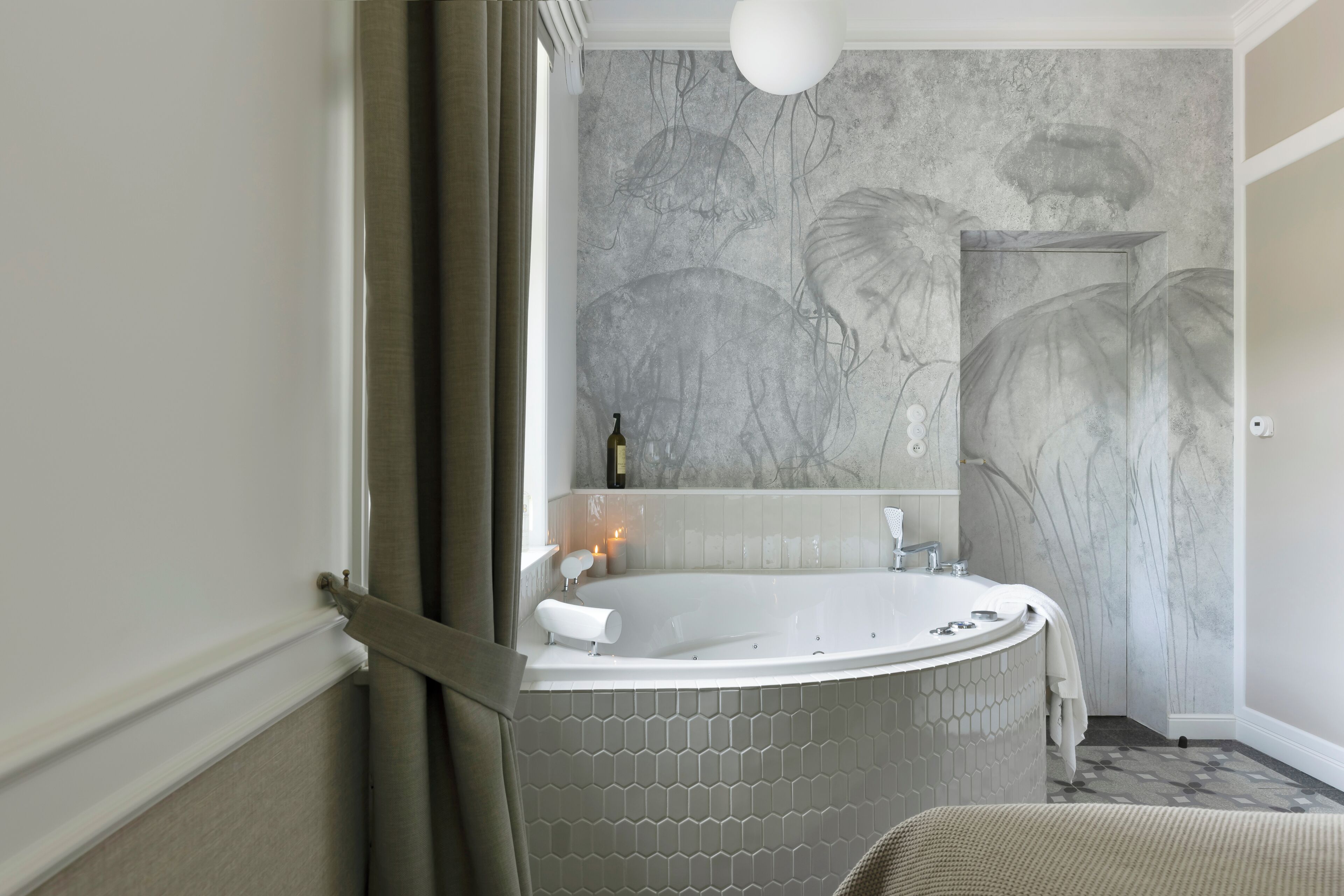 A modern bathroom with a freestanding bathtub, a large mirror, and a hexagonal tile floor.