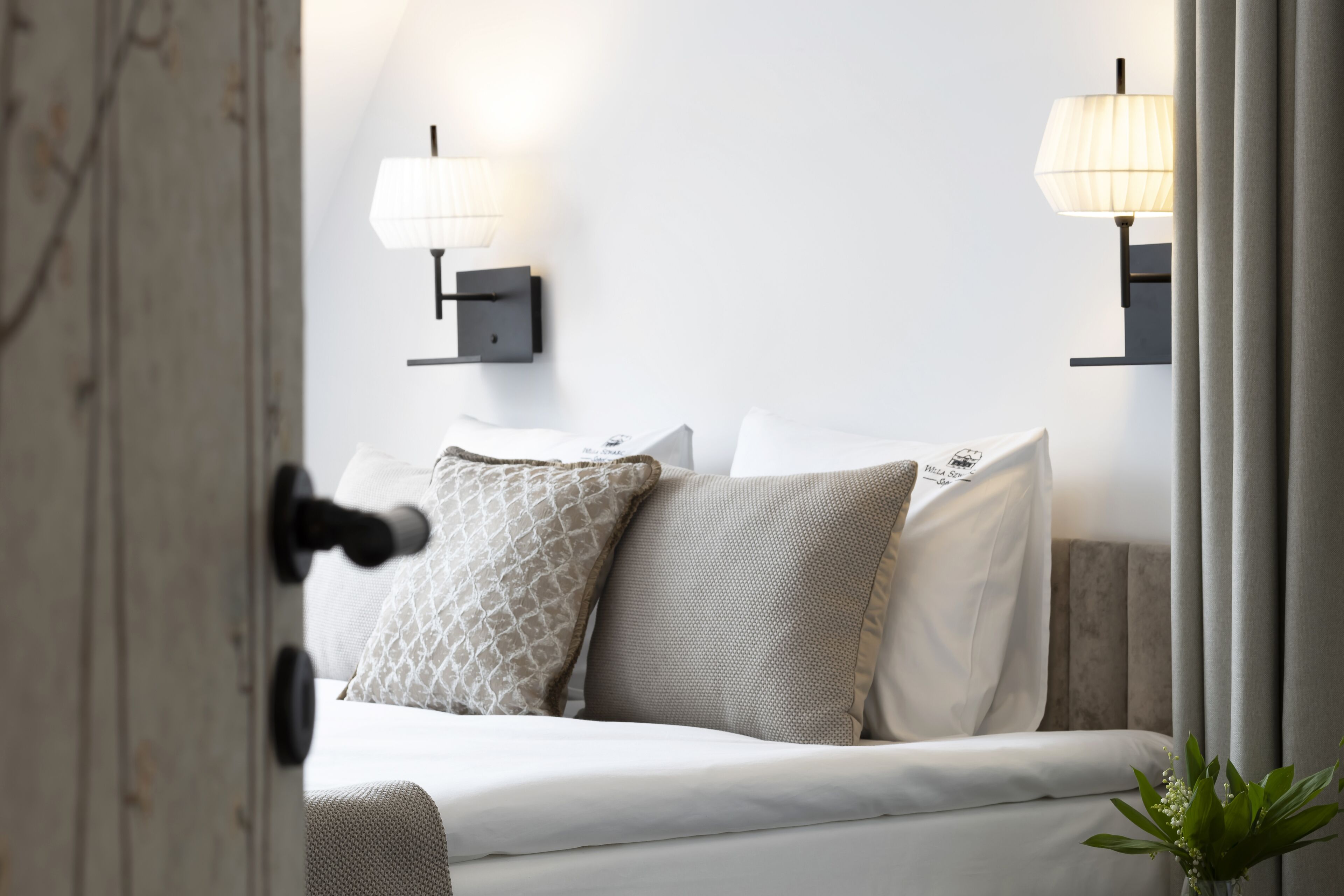 Ein Schlafzimmer mit einem Bett, zwei Wandlampen und einer Tür.