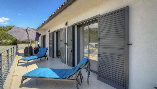 Un balcon avec deux fauteuils bleus, un espace abrité et une vue sur le paysage.