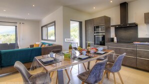 Une cuisine moderne avec des meubles de rangement aux couleurs sombres, un four encastré et une grande fenêtre.