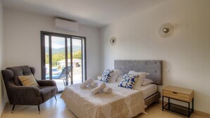 Une chambre à coucher avec un lit, une chaise, une table de chevet et une vue sur l’extérieur.