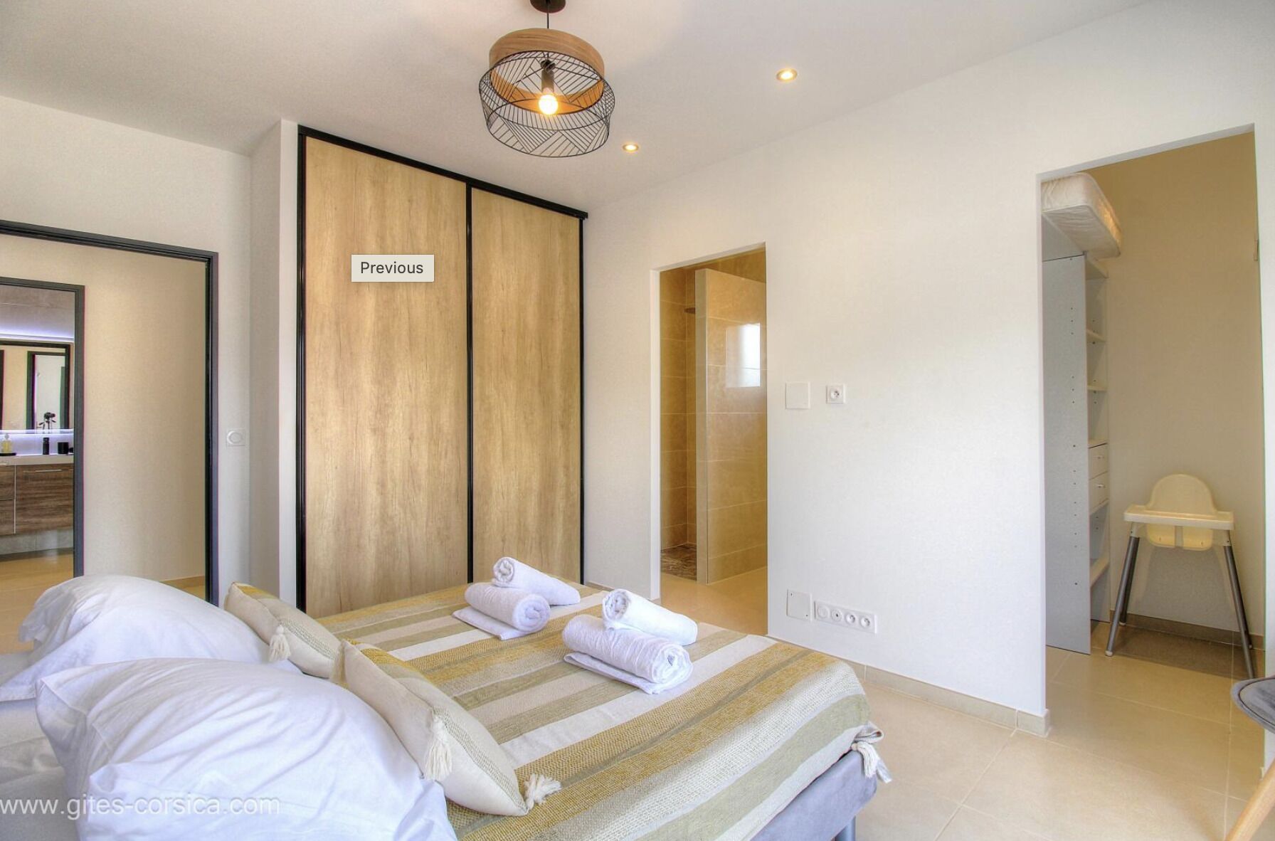 Ein modernes Schlafzimmer mit Bett, Kleiderschrank, Duschbereich und einem Sessel.