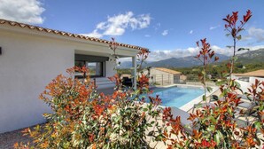 Une villa moderne dotée d’une piscine, entourée d’une végétation luxuriante et avec des montagnes en toile de fond.