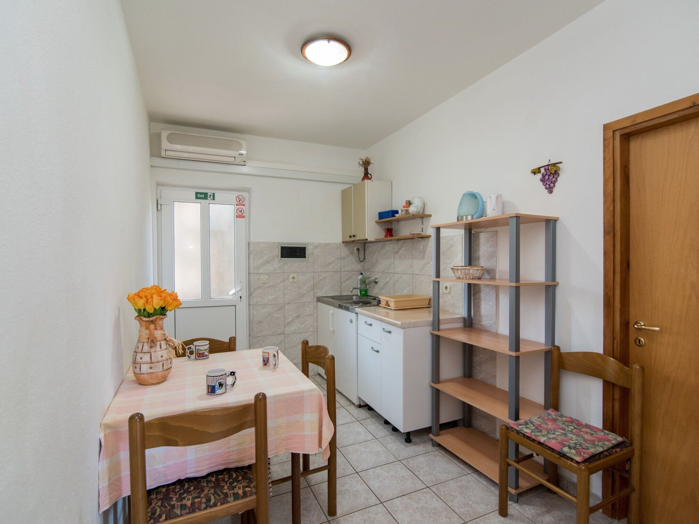 A compact kitchen with a dining table, chairs, a sink, and a small refrigerator.