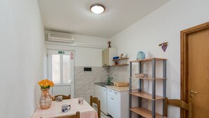Una cucina compatta con tavolo, sedie, lavandino e un piccolo frigorifero.
