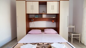 Una camera da letto con un letto, due cuscini, un comodino con una lampada e un armadio con due ante.