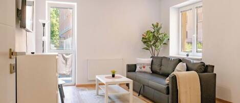 A modern living room with a grey sofa, a small white coffee table, and a potted plant.