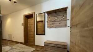 A hallway with a wooden floor, a patterned rug, a wooden bench, a mirror, and a wooden wardrobe. - Apartment Aiko by Interhome (Längenfeld)