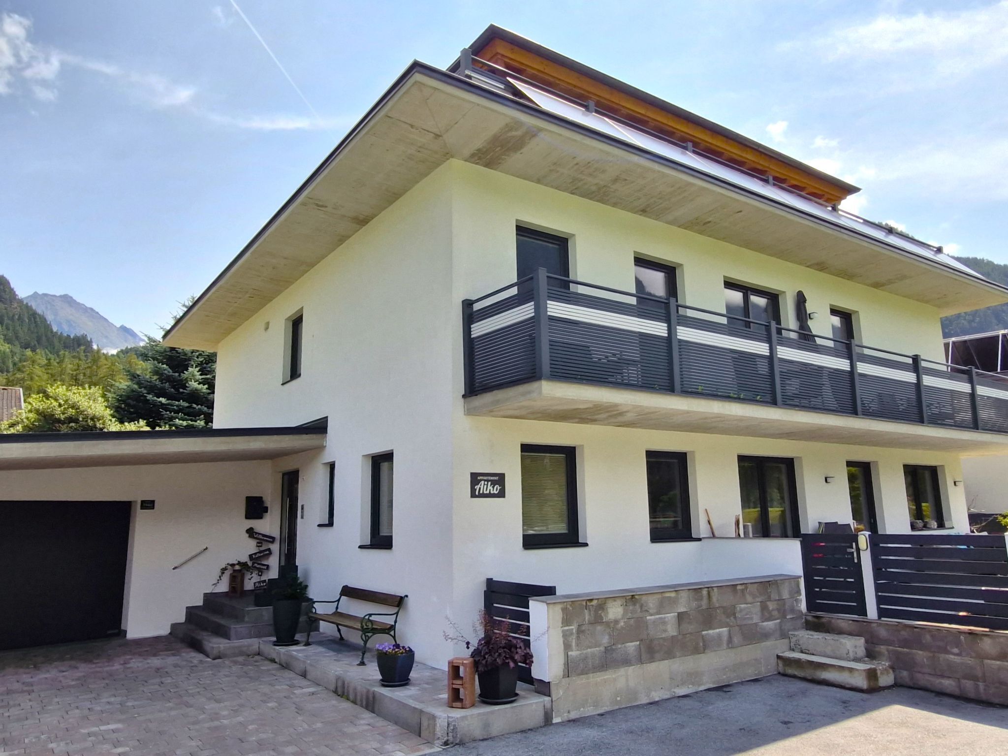 A two-story building with a balcony, a garage, and a bench outside.