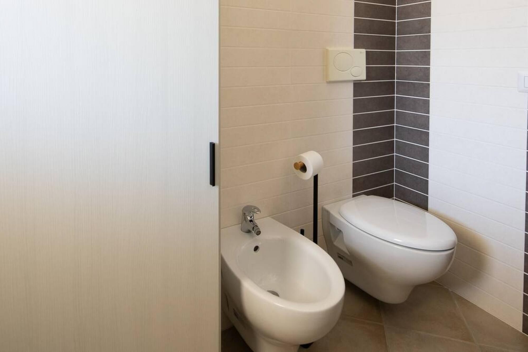 A small bathroom with a bidet, toilet, and a towel rack.