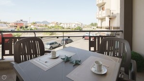 A balcony with a table set for two, two chairs, a coffee cup, and a spoon on a placemat. - Welcomely - Xenia Boutique House - Apt 1 (Olbia)