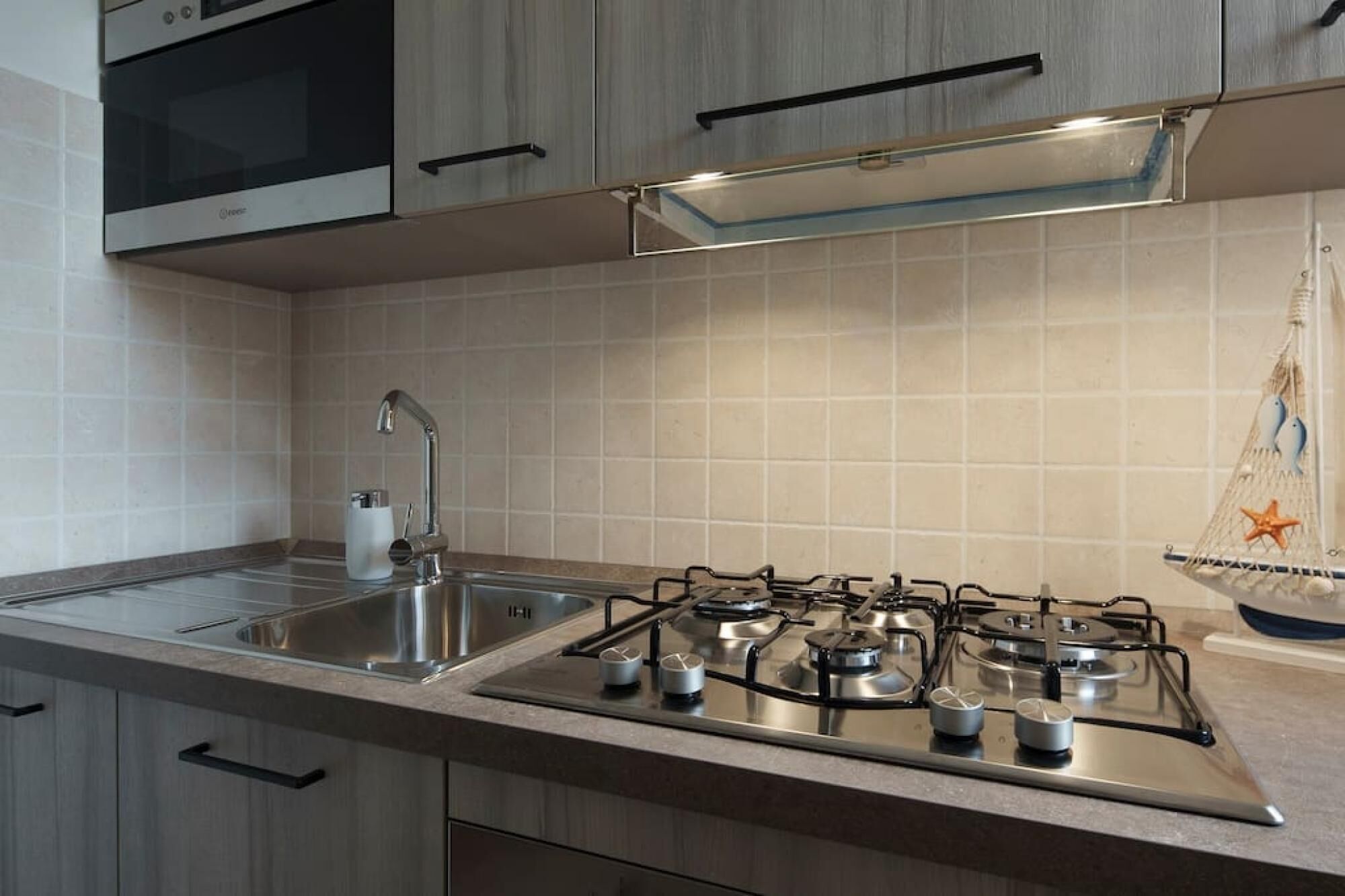 Una cucina moderna con piano cottura in acciaio inossidabile, lavello e pensili in legno.