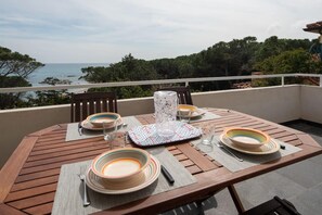 Enjoy a serene meal on the balcony with a stunning sea and greenery view.