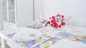 A dining table with floral tablecloths, two wine glasses, and a magazine. - Welcomely - Villa Oleandro (Muravera)