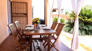 A wooden dining table set with plates, bowls, and a vase of yellow flowers.