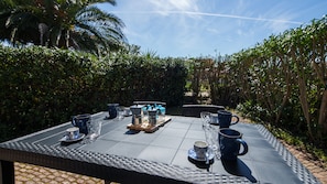 An outdoor dining table set with blue and white patterned cups, a coffee pot, and a tray.