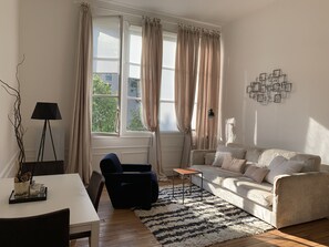 Un salon avec un canapé, un fauteuil, une petite table et une lampe.