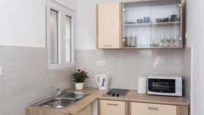 Een praktische keuken met een spoelbak, een magnetron en een kast met glazen deuren.