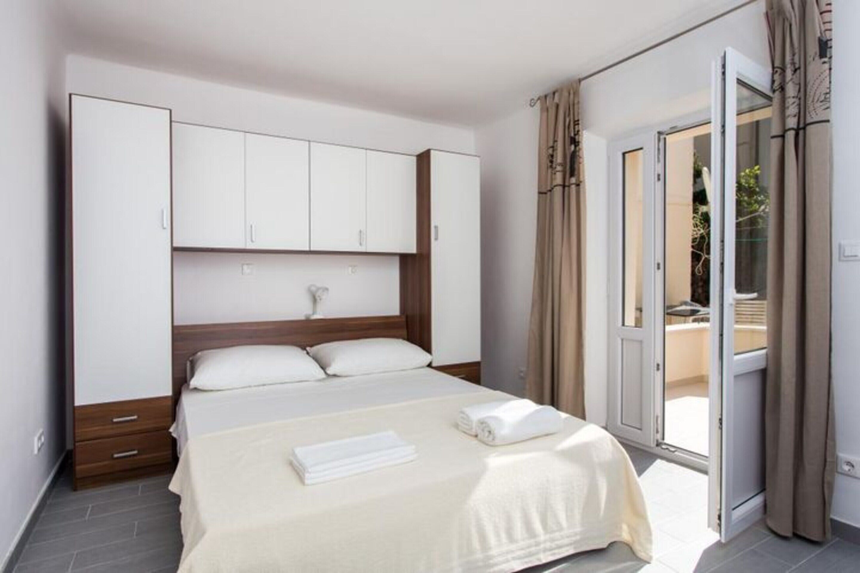 A hotel room with a bed, a wardrobe, and a sliding glass door to the outside.