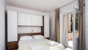 Een hotelkamer met een bed, een kledingkast en een schuifdeur naar buiten.
