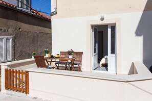 A small outdoor patio with a table and chairs, a wooden gate, and a door leading to a room. - Apartment Maricol - One Bedroom Apartment With Terrace (Dubrovnik)