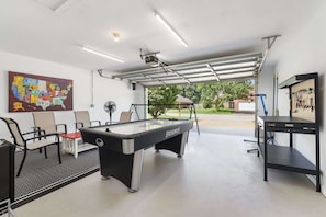 A pool table in a room with a ceiling fan, chairs, and a map on the wall.
