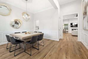 A dining area with a wooden table, black chairs, and pendant lights.