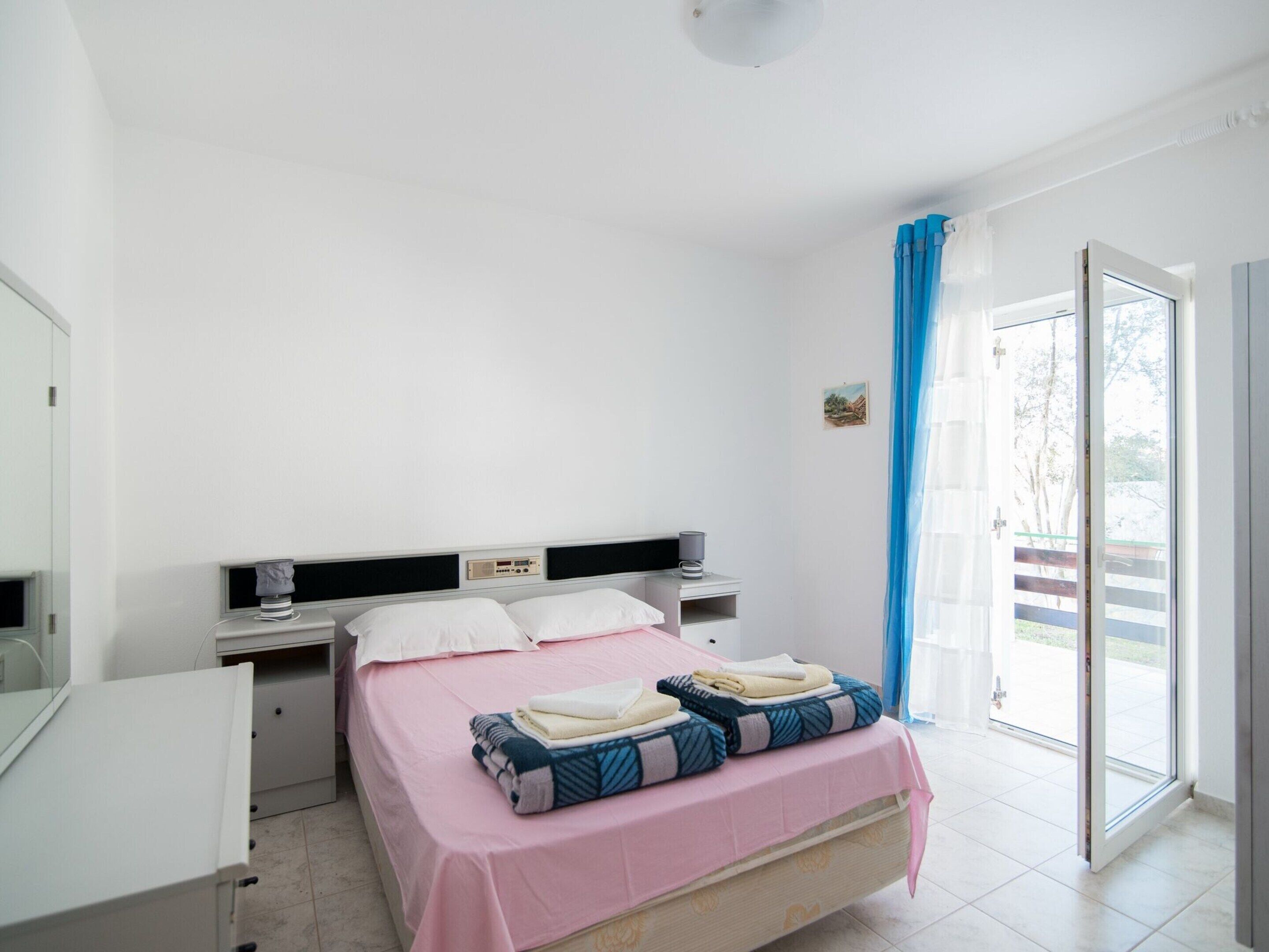 A bedroom with a bed, bedside tables, a desk, and a window with curtains.